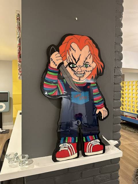 Life-size killer doll character wall piece with glossy resin finish mounted on a dark wall